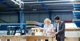 Woman and man business people having meeting in factory.